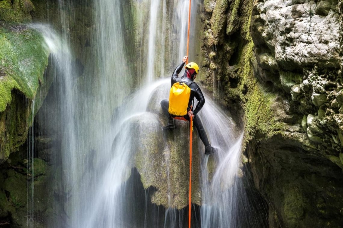 Bucket list adventures: Man rappelling down a waterfall