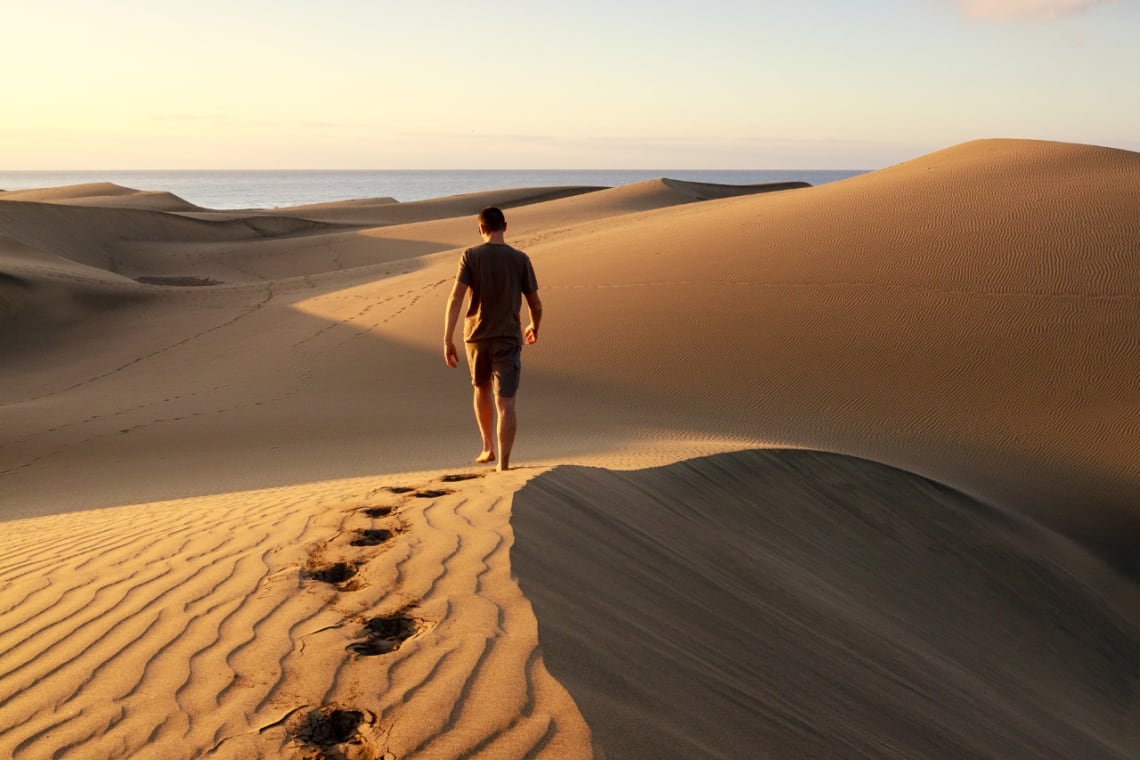 Chico caminando por dunas de arenas en Canarias
