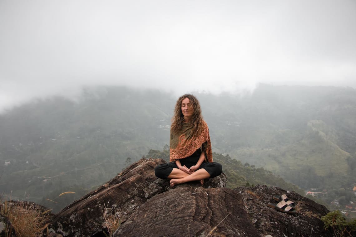 Mujer meditando en una montaña. La meditación puede ayudarte a cambiar tu estilo de vida