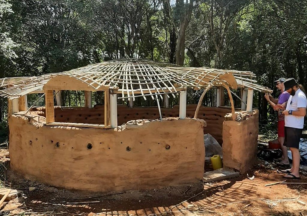 Dos hombres construyendo una casa ecológica con paredes de adobe