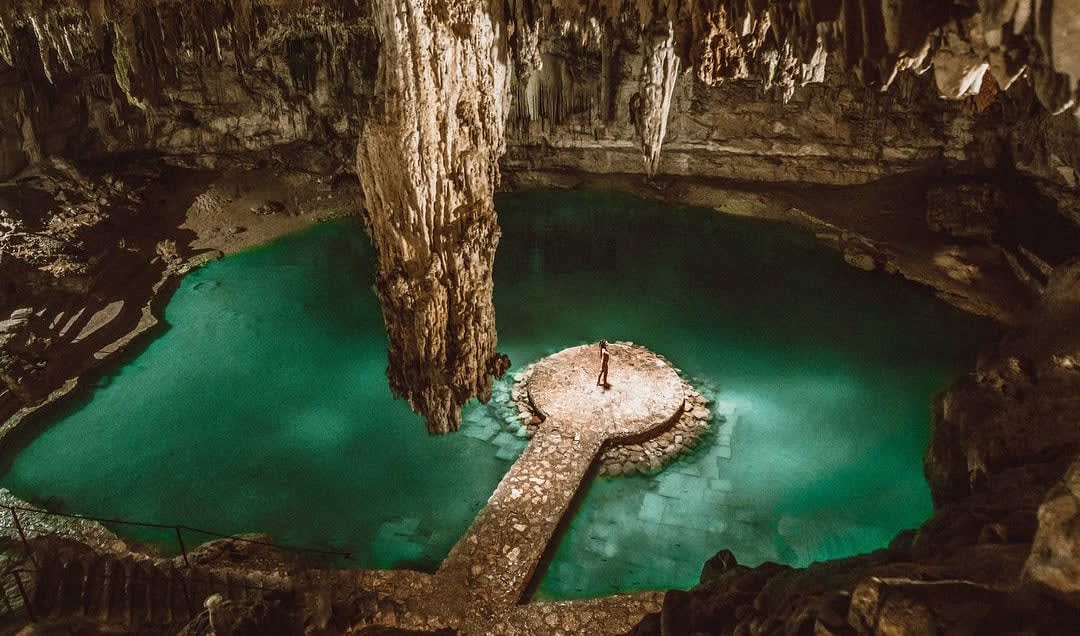 Cenote seen from above with girl in a platform