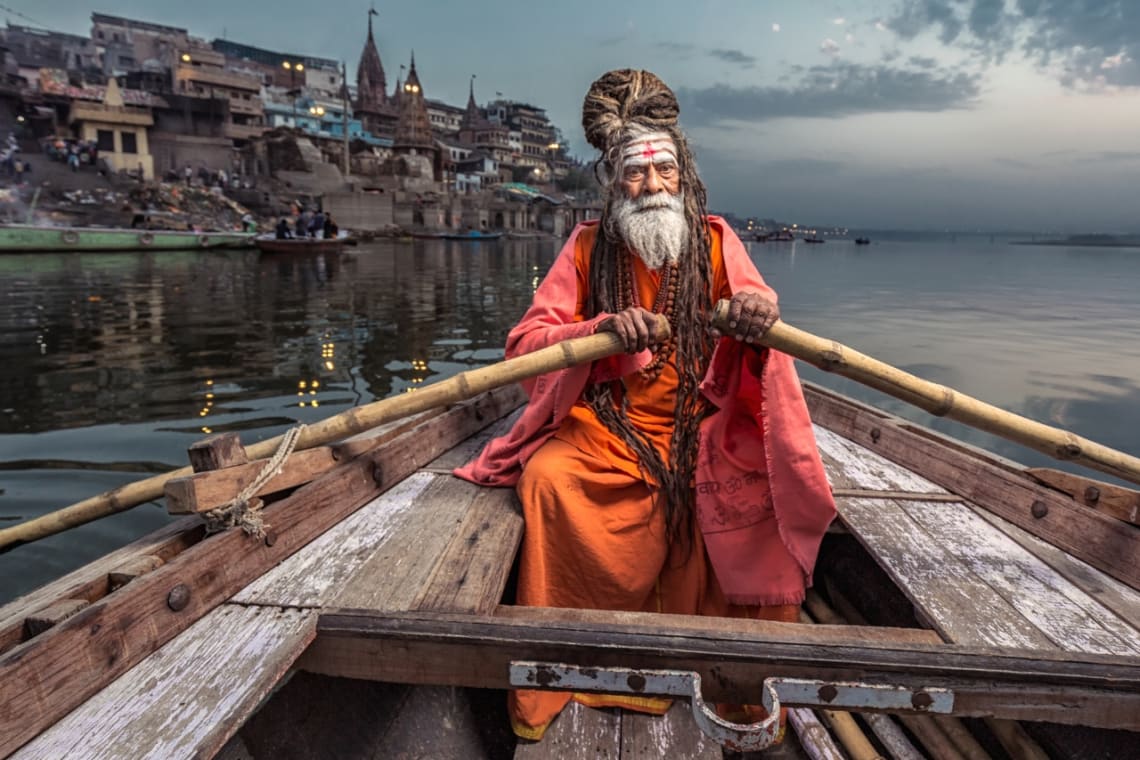 Sadhu (religious ascetic) rowing in Ganges River, Varanasia, India