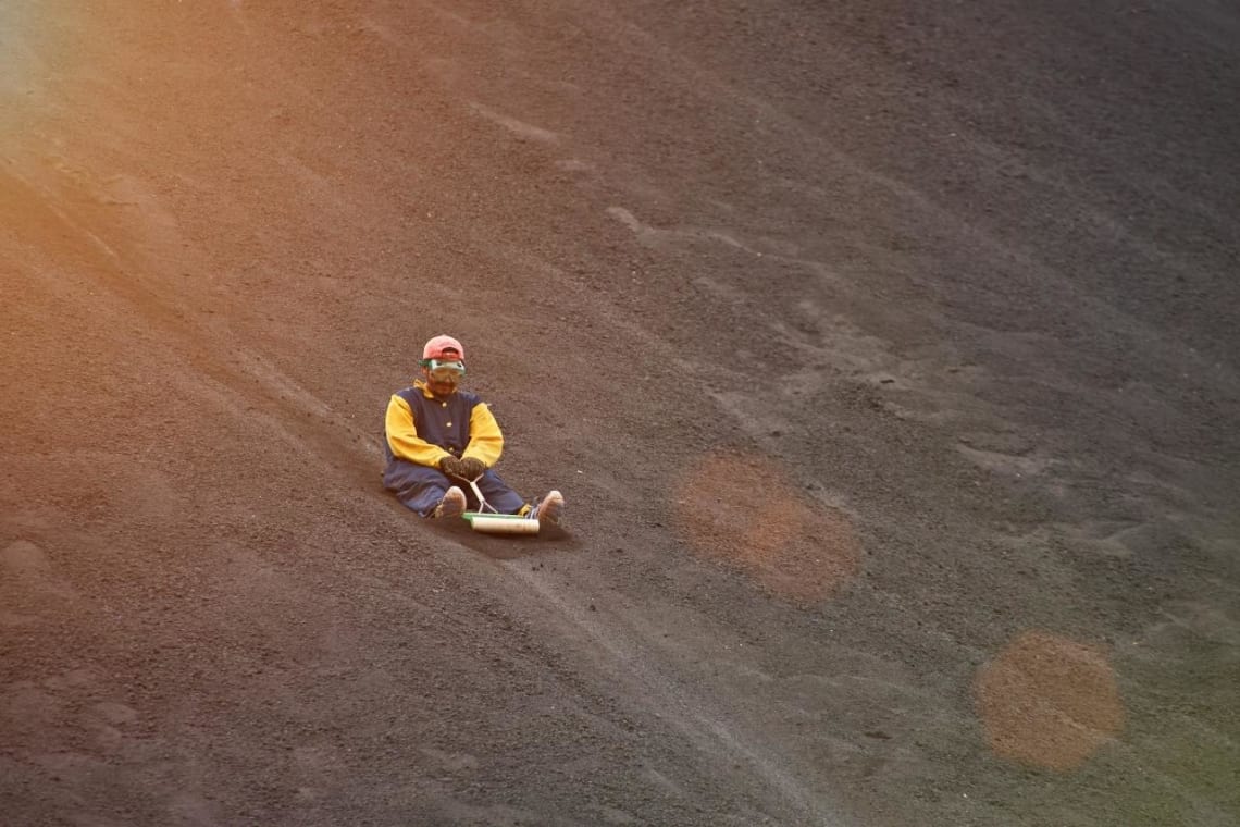 Guy sliding down a volcano in Nicaragua