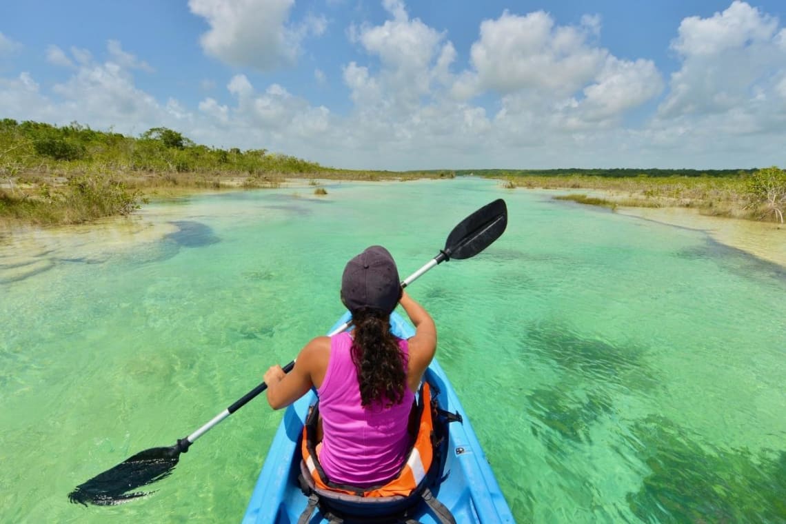 Chica haciendo kayak en Laguna Bacalar, México, una de las actividades ecoturísticas