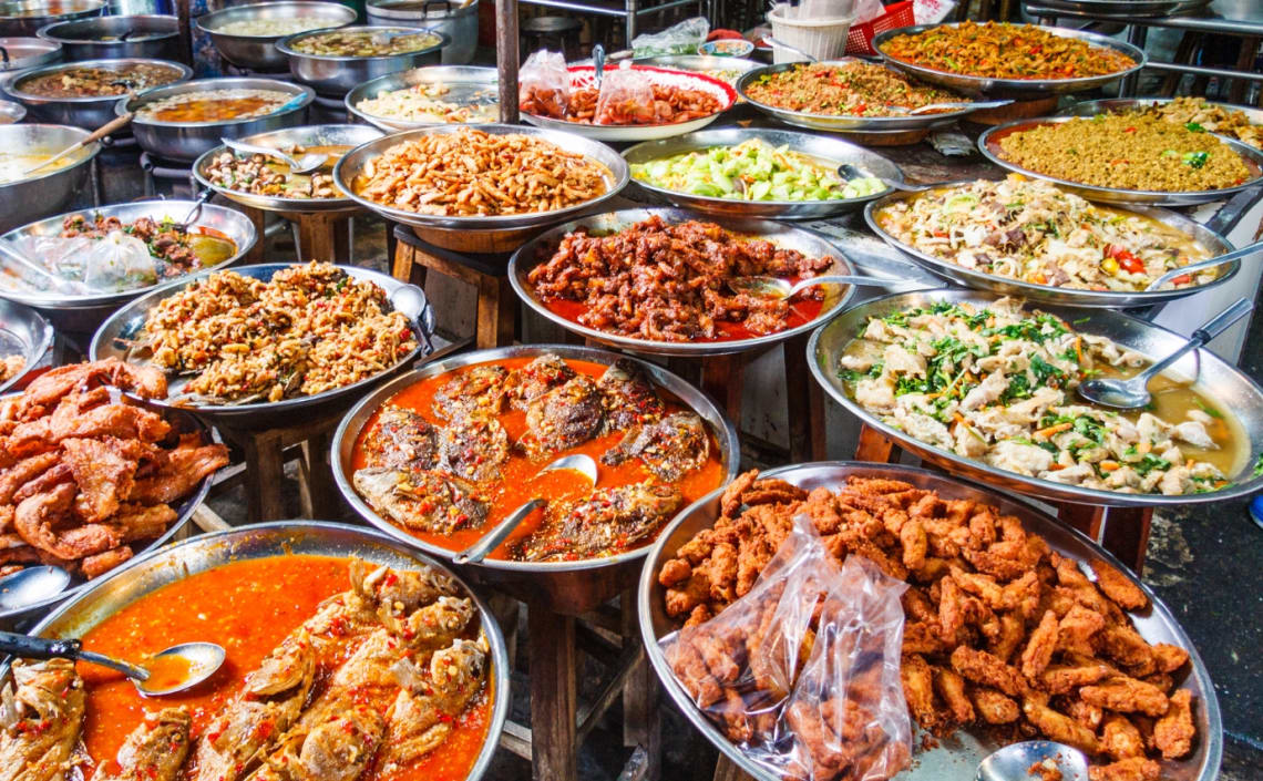 Puesto callejero con muchas bandejas de comida a la vista