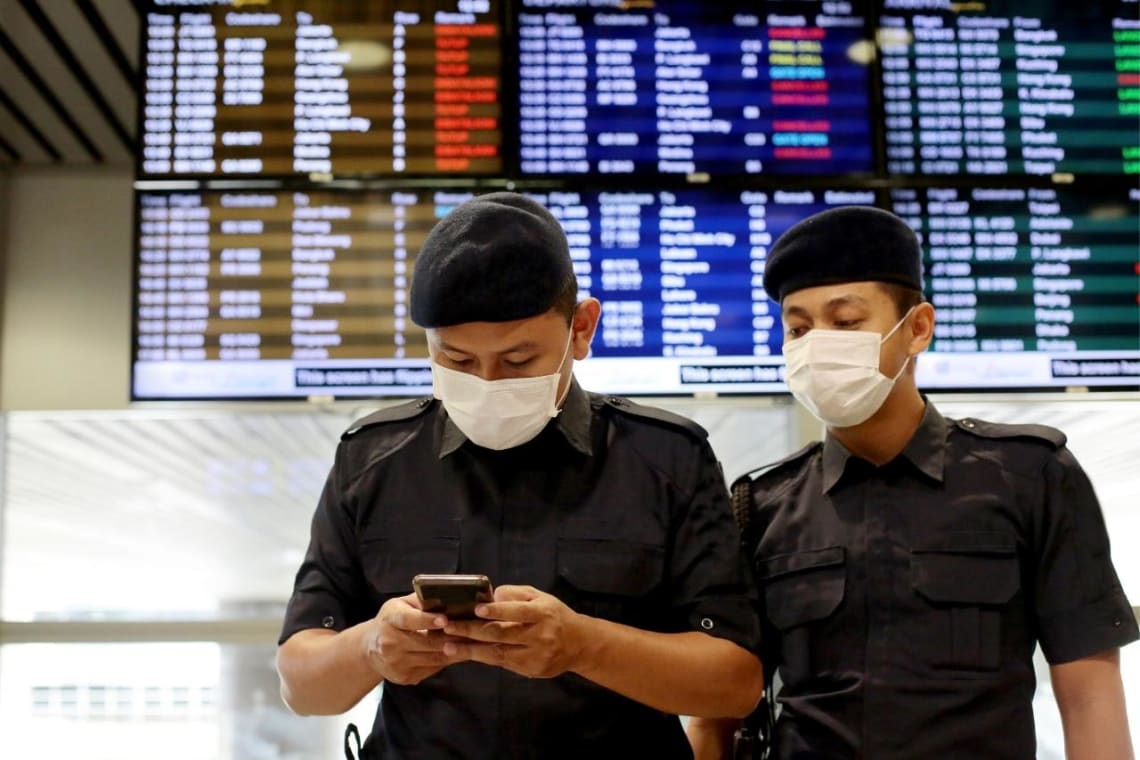 Policías tailandeses en aeropuerto controlando documentos de viaje en un celular