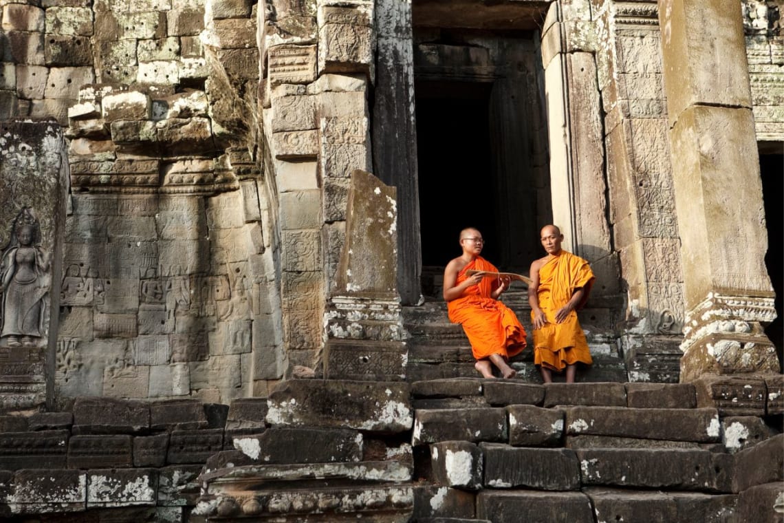 Dos monjes budistas sentados en escalera de templo en Angkor