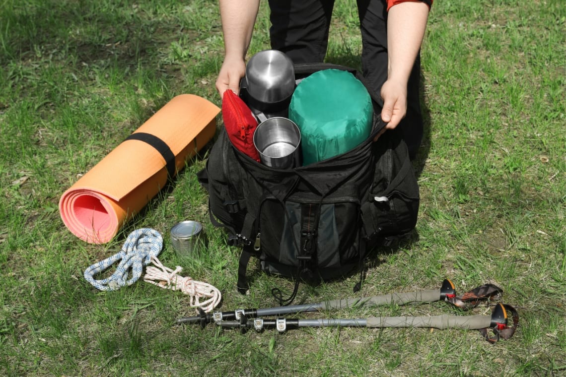 Backpacking checklist: hands of a person packing a backpack with camping gear