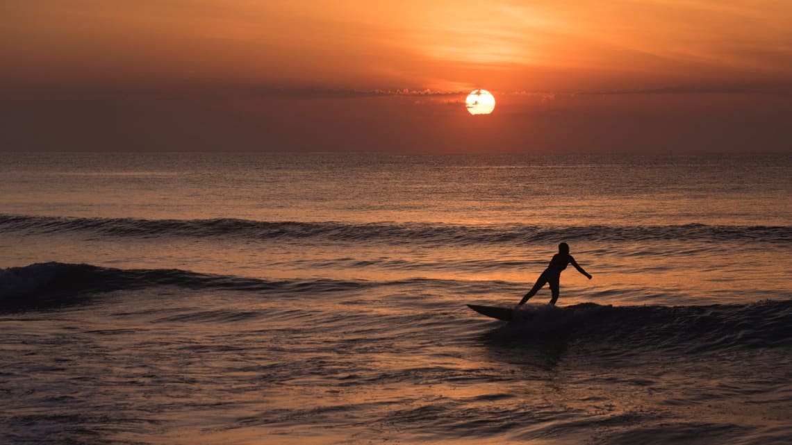 Chica surfeando al atardecer en Ubatuba