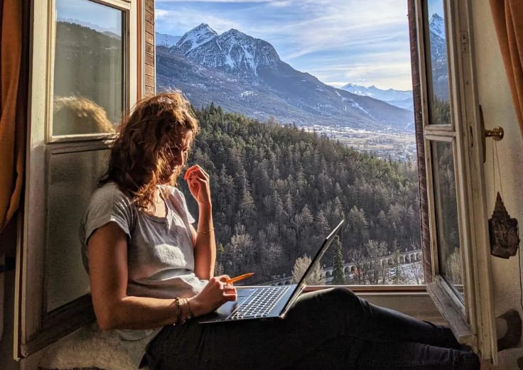 girl working on her laptop on the window of a coliving space