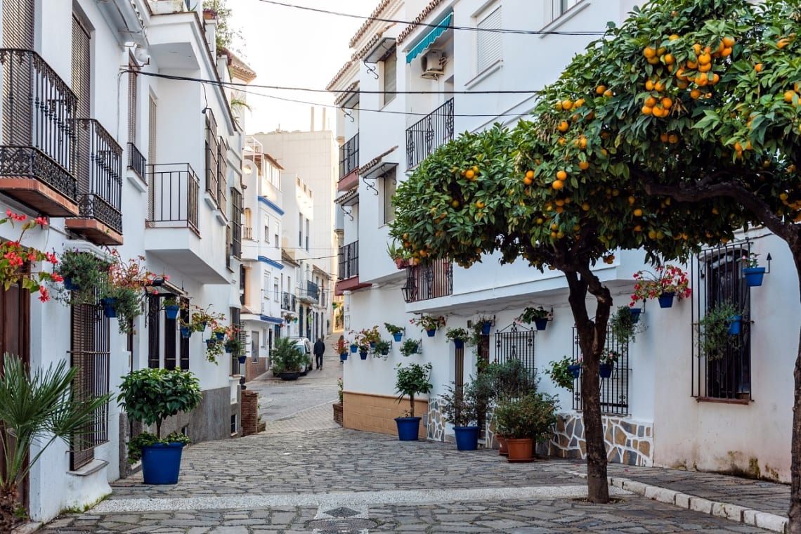 Calle peatonal con naranjos y casa blancas en Estepona, Mediterráneo de España