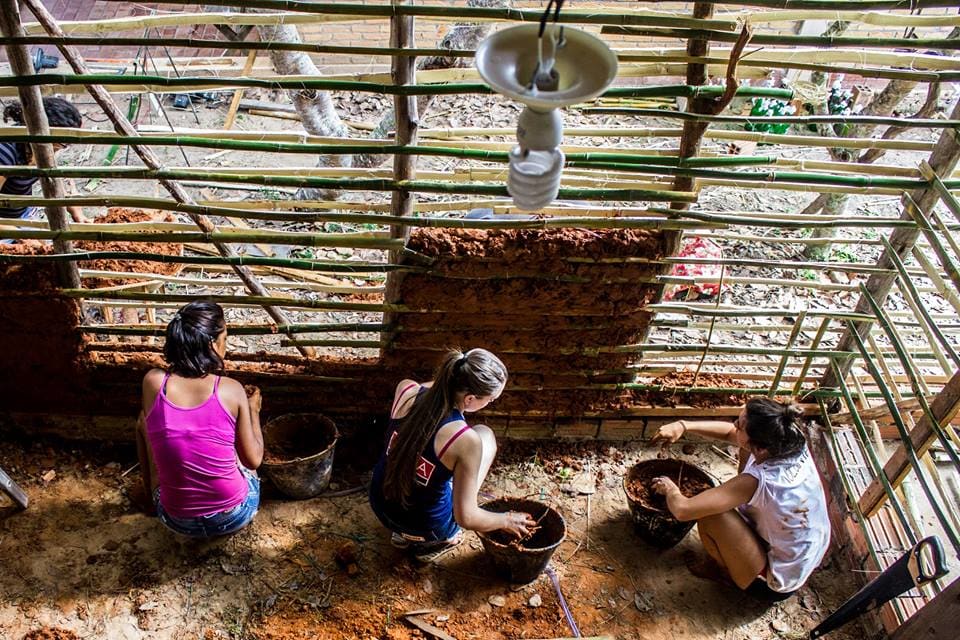 Three girls building a wall with eco construction techniques in an off-the-grid community