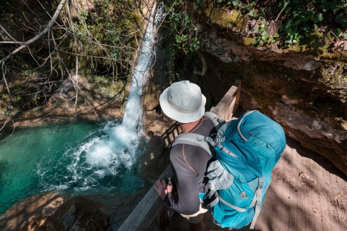 Viajero con mochila observando una cascada desde mirador