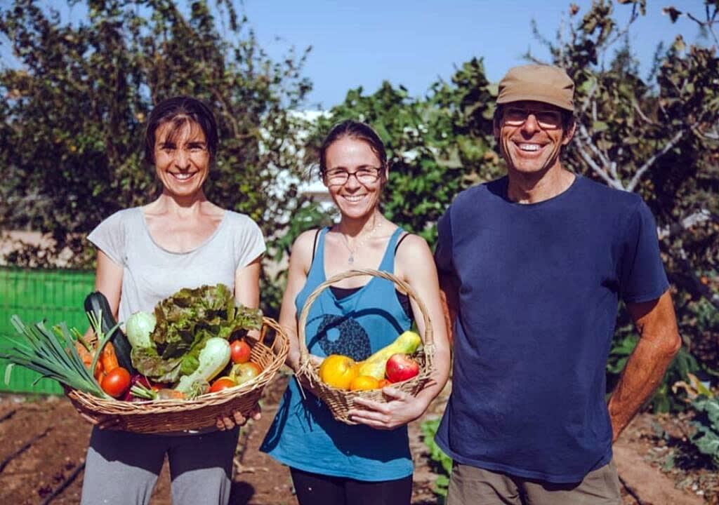 Smiling farmers showing two baskets of freshly picked vegetables and fruits