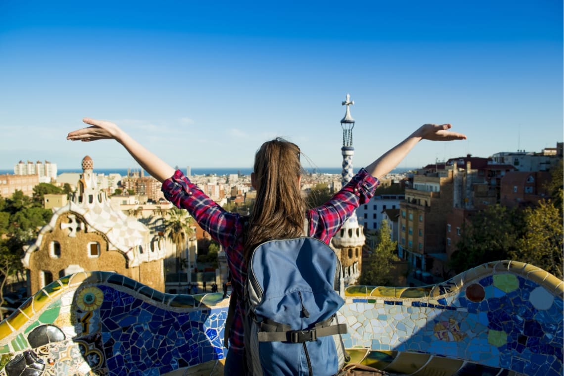 Joven viajera alzando los brazos de felicidad en Park Güell, Barcelona