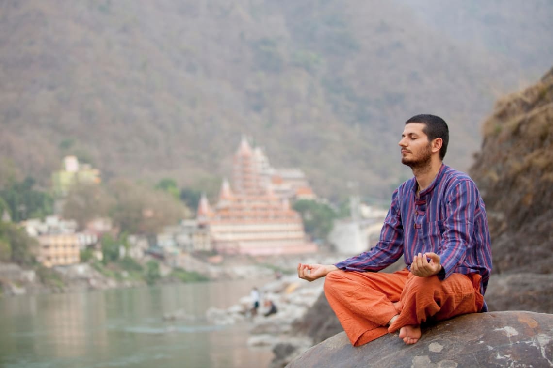 Young man meditating in a rock in Rishikesh, India