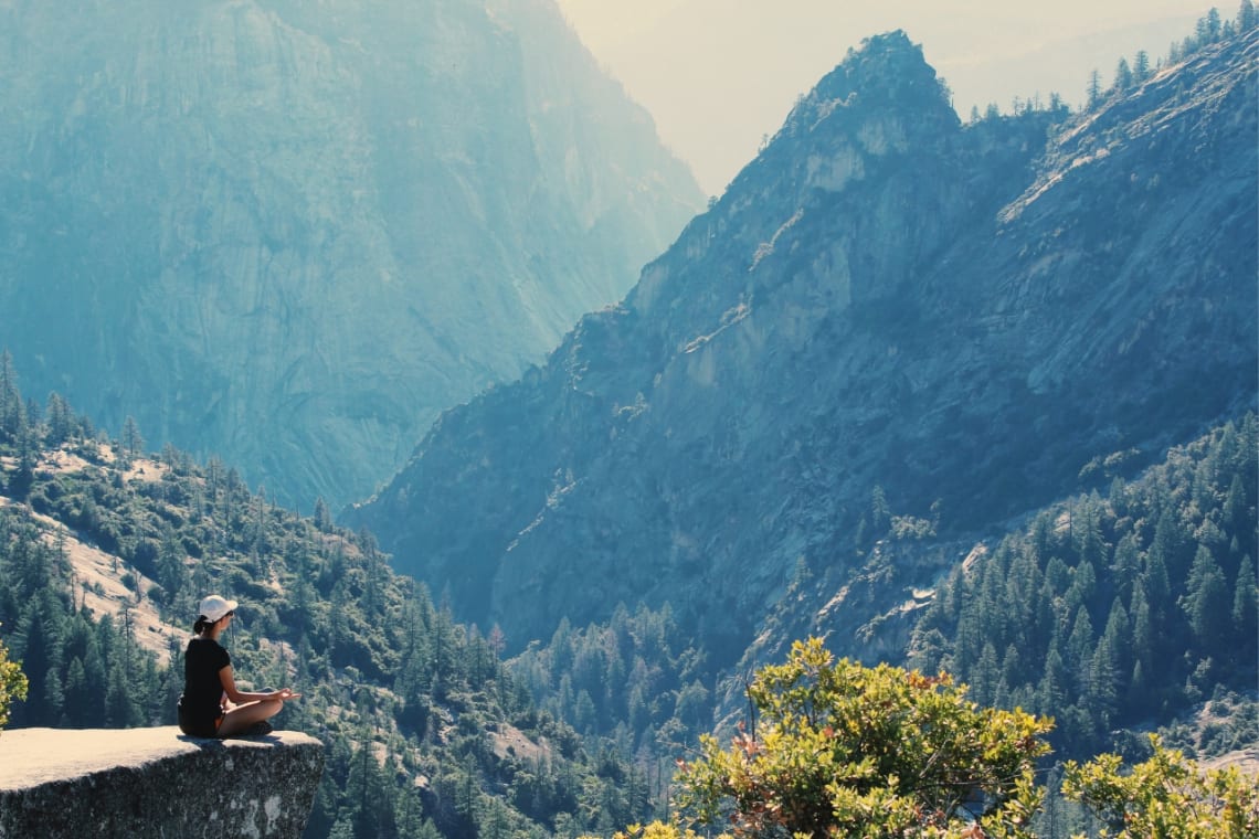 Young woman meditating in a mountainous environment during her spiritual travel experience