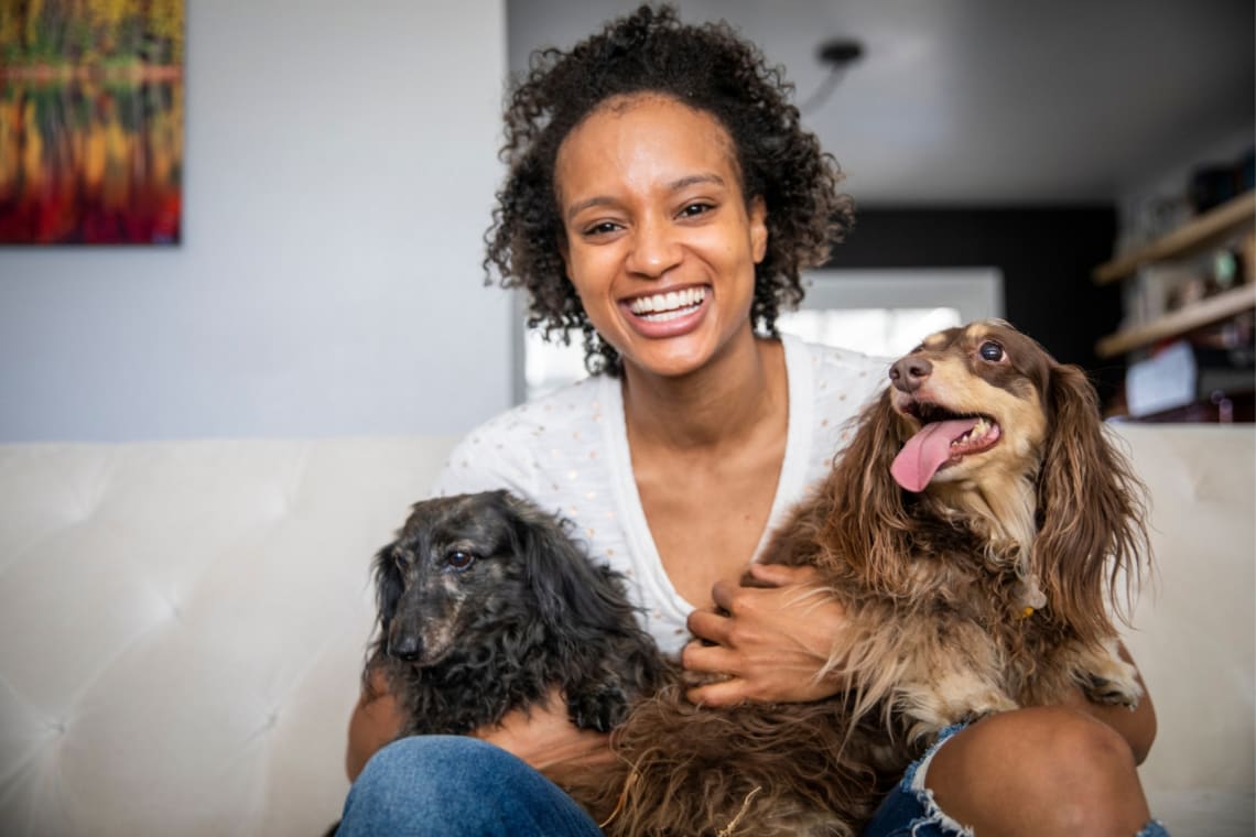 Smiley house sitter hugging two dogs