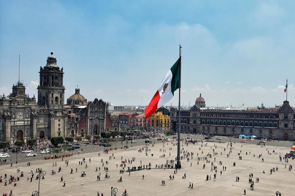 Vista de el Zócalo con mástil en el centro y gente paseando