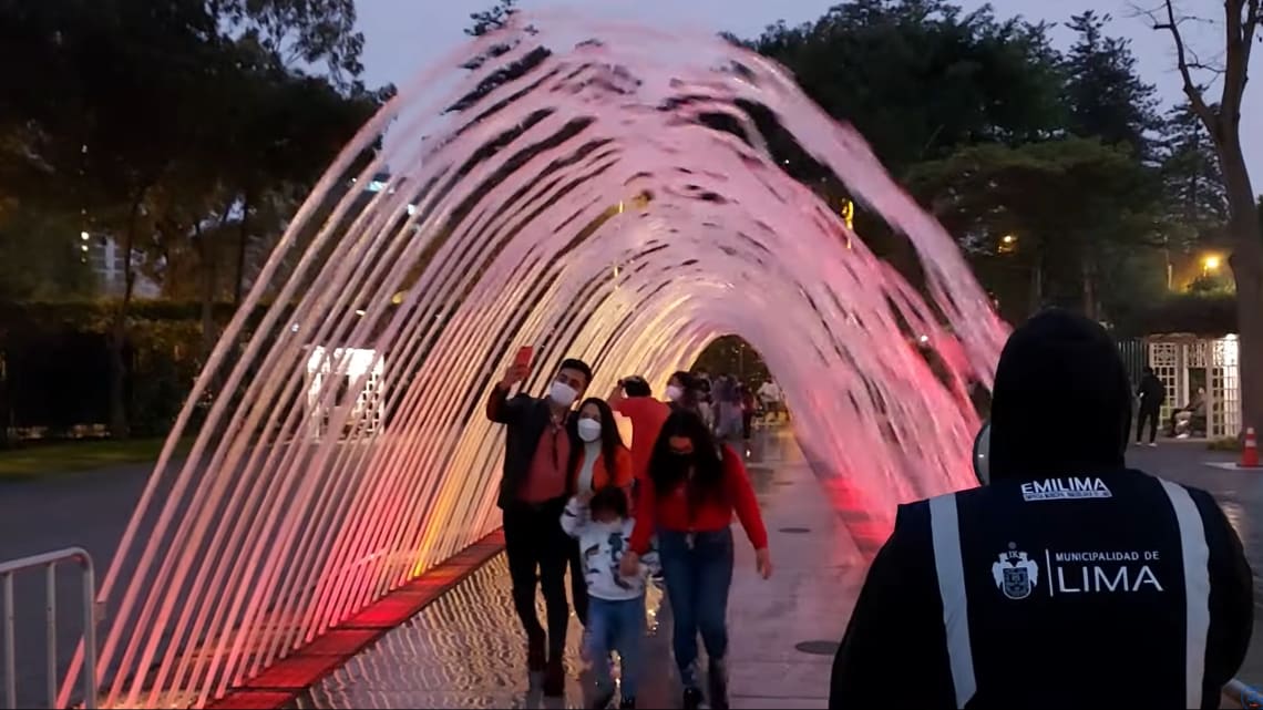 Familia pasando por debajo de un "arco" de agua 