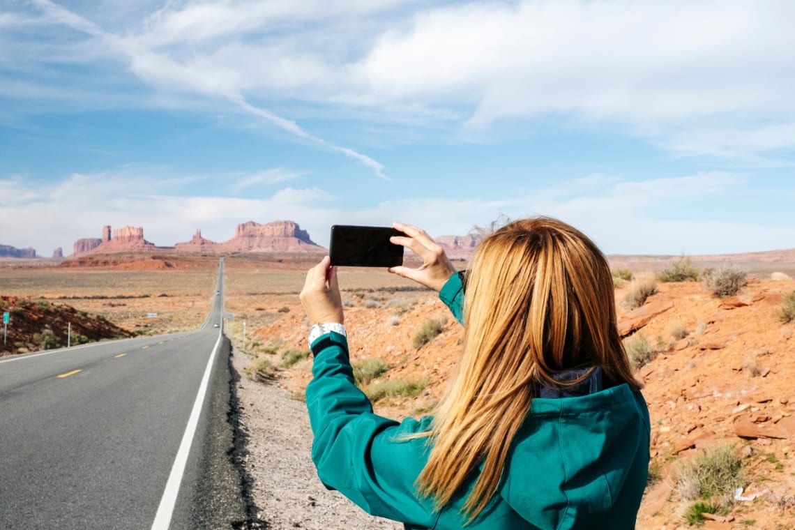 Chica sacando foto con teléfono en ruta hacia el Cañón del Colorado, Estados Unidos