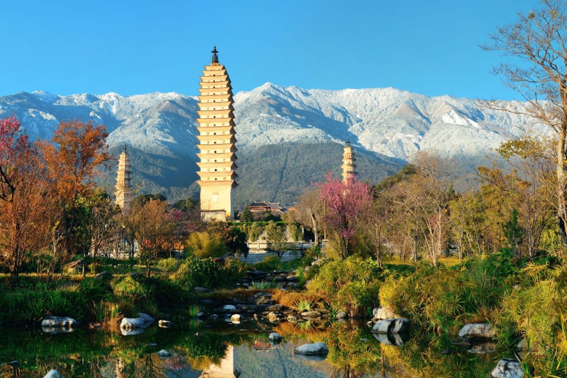 Construcciones budistas junto a un arroyo y montañas nevadas de fondo en Dali, uno de los lugares tranquilos de China