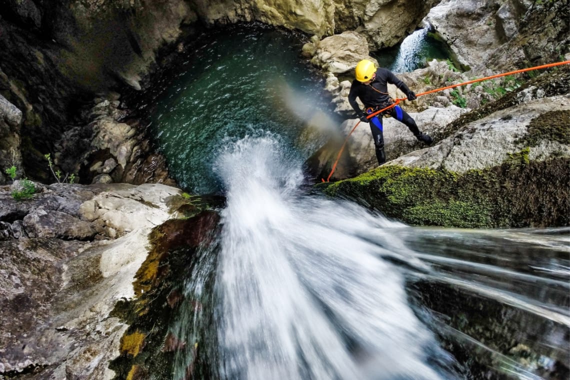 Actividades ecoturísticas: Hombre descendiendo en rappel junto a una cascada