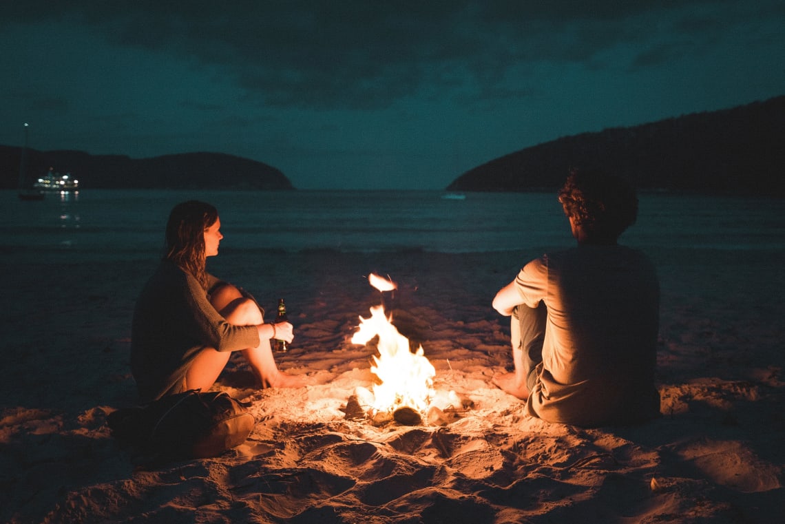 Couple enjoying a beach bonfire, Tasmania, Australia