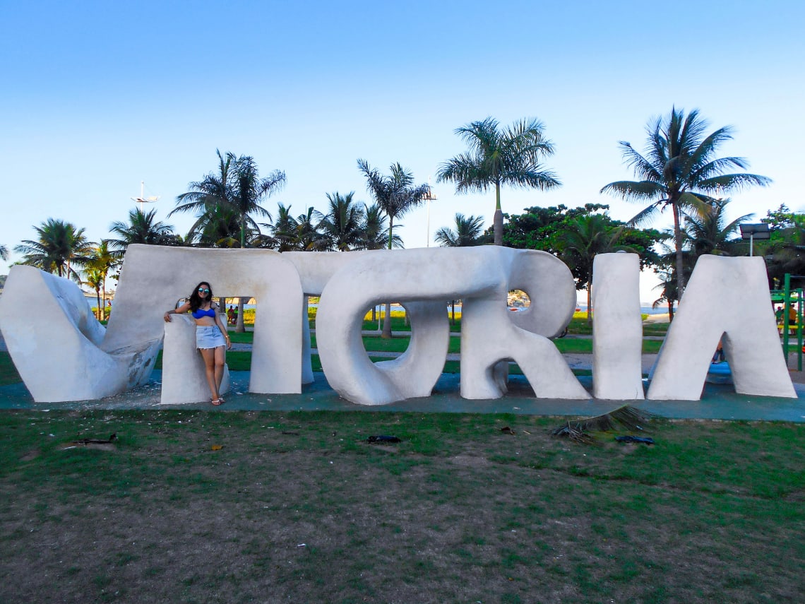 Mulher posando com o nome da cidade em Vitória, ES