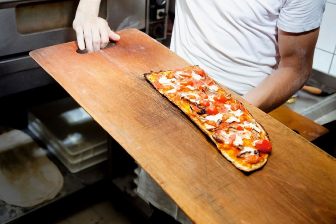 Pizza chef taking a vegan pizza out of the oven