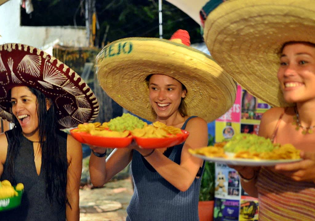 Three girls with mexican huts serving nachos