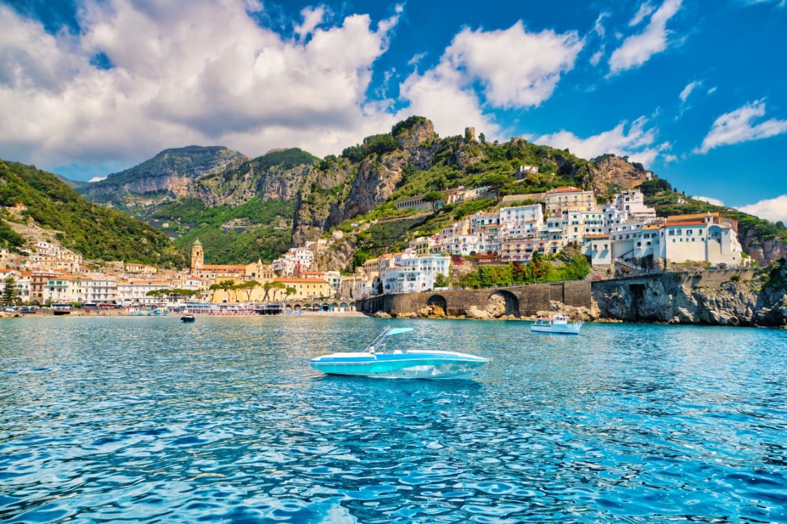Pueblo costero de Amalfi con casas en una colina visto desde el agua