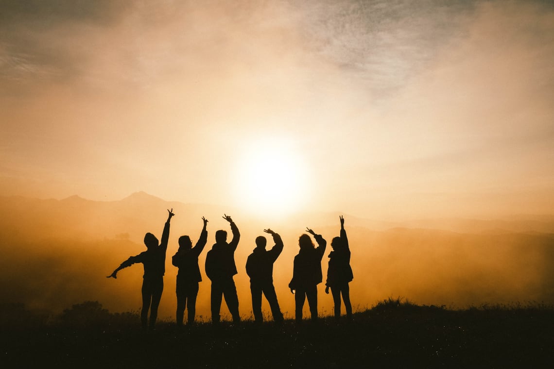 Friends on a mountaintop at sunset