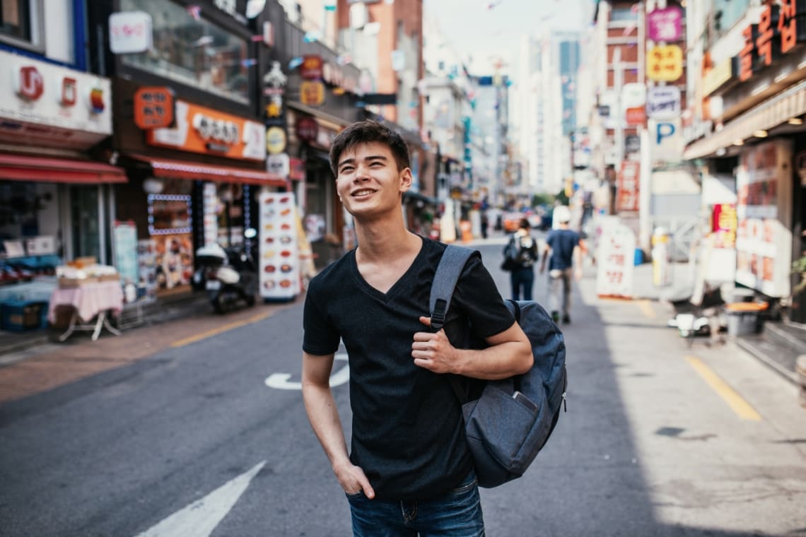 Happy young guy in South Korea during a solo backpacking journey