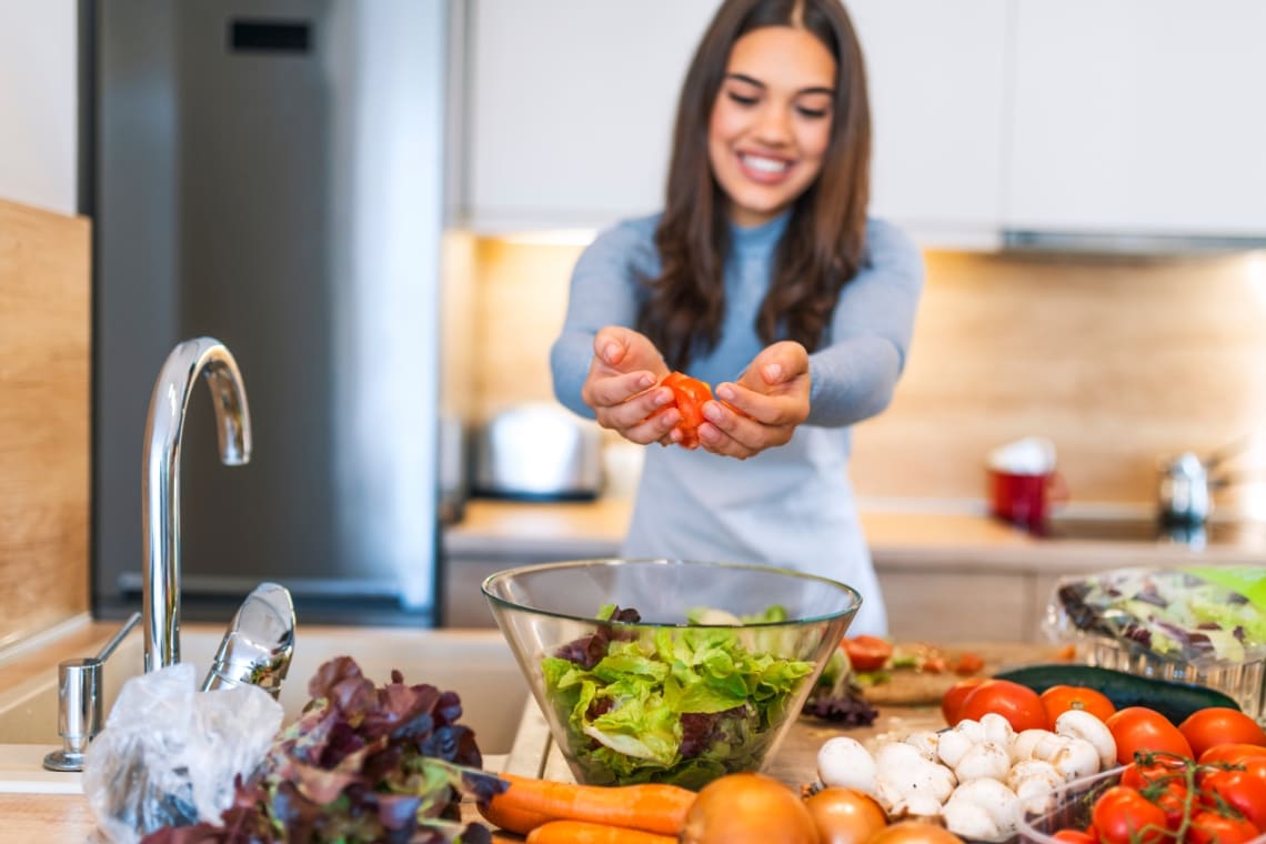 Young girl making a salad with vegetables from her organic garden