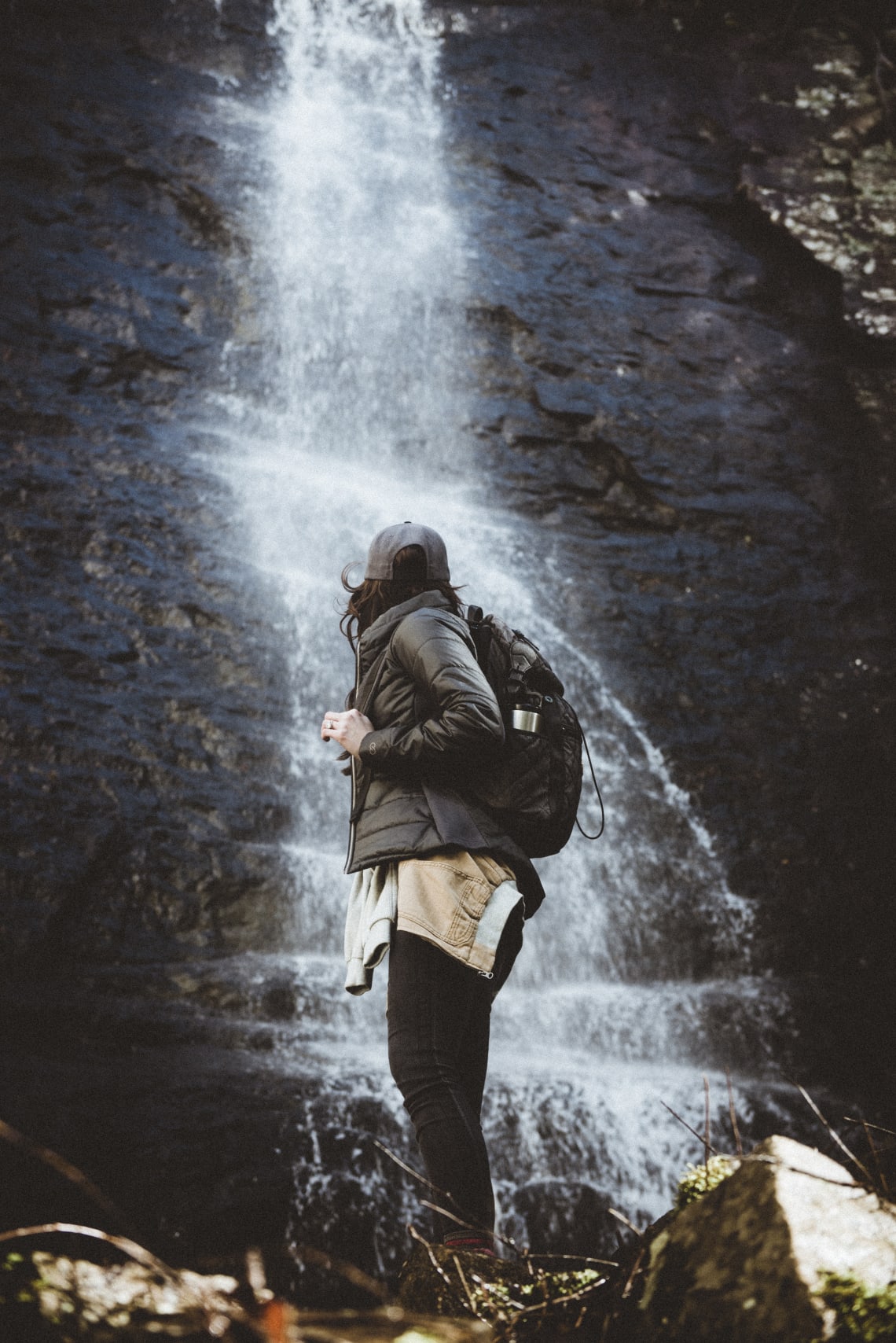 Solo female traveler standing in front of a waterfall