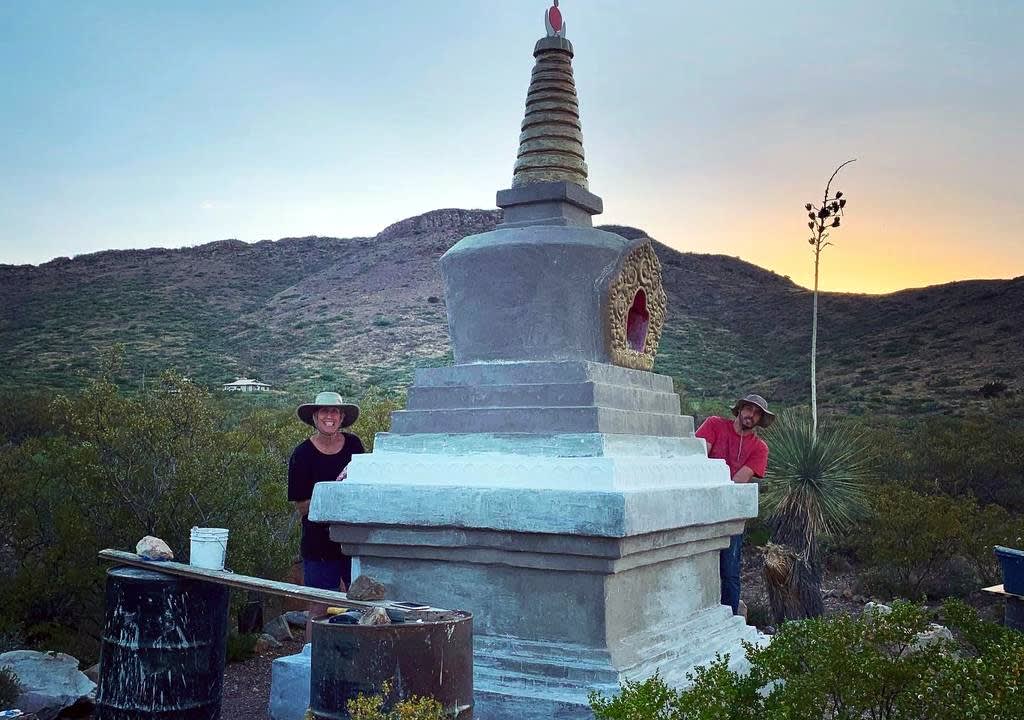 Two volunteers renovating a Buddhist stupa in a spiritual retreat center