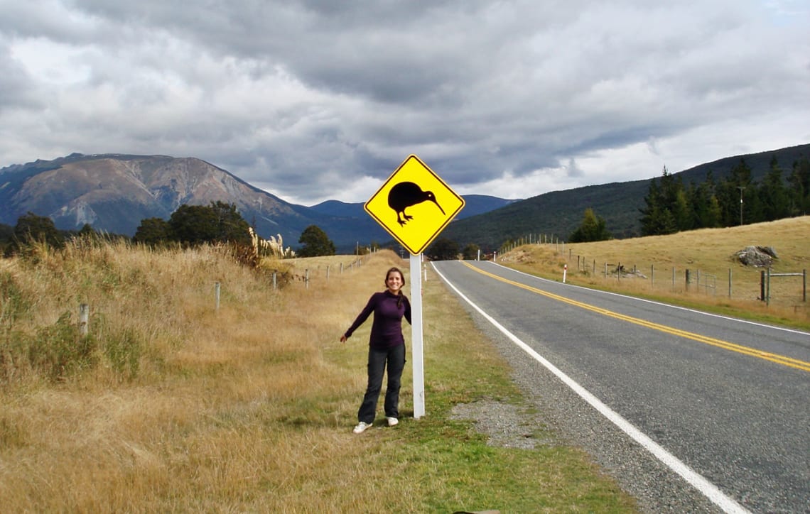 Posando junto a una señal de la ruta que advierte cruce de kiwis en Nueva Zelanda