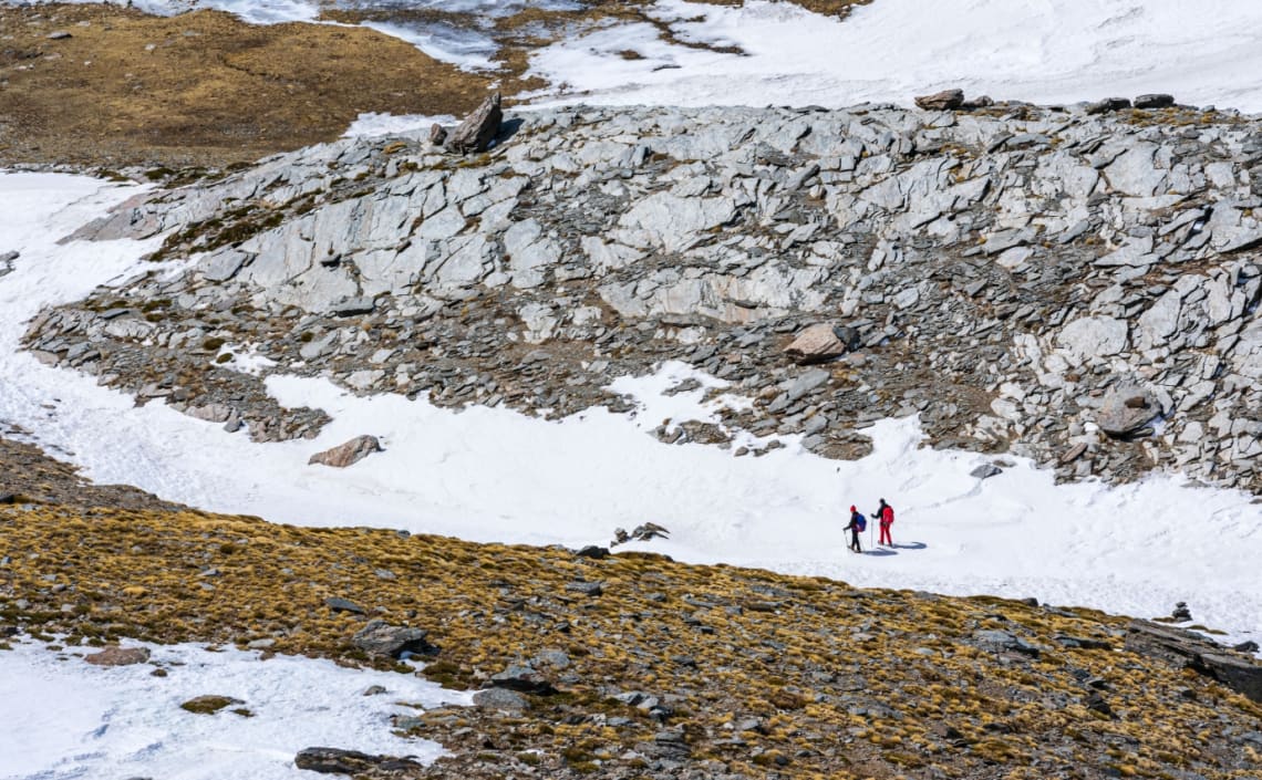Dos personas haciendo senderismo por camino nevado en el Parque Natural de Sierra Nevada