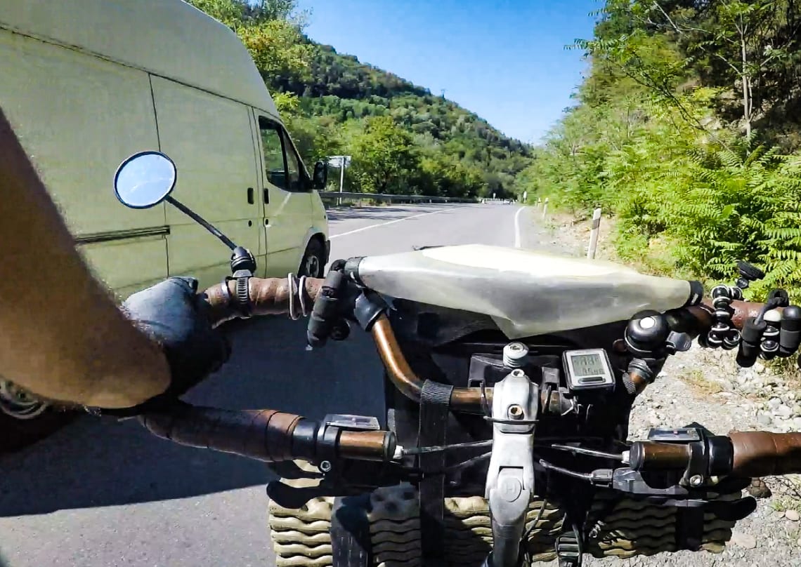 Andando en bicicleta por el costado de una angosta carretera