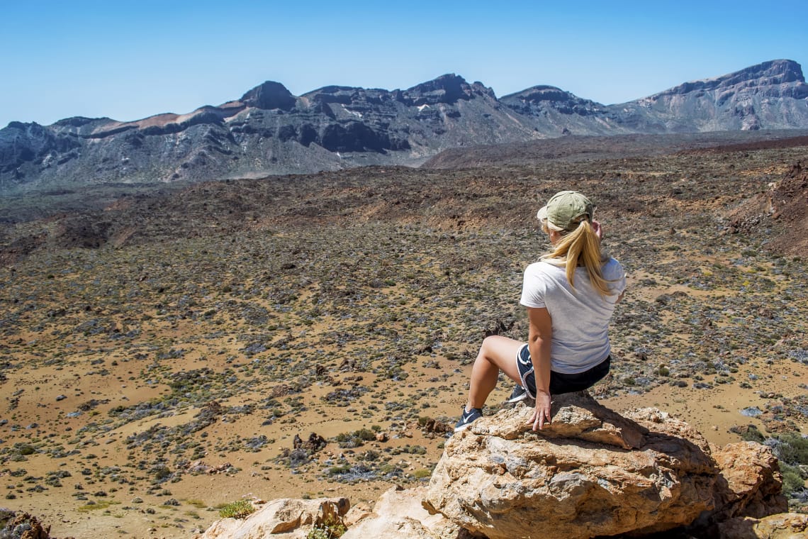 Qué es y cómo funciona un intercambio de trabajo: la guía completa - Worldpackers - mujer sentada sobre roca mirando el horizonte  