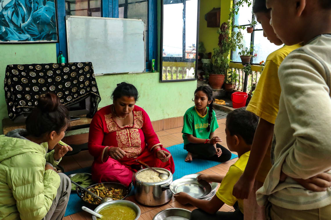 Haciendo un voluntariado en Nepal como profesora - Worldpackers - familia  en Nepal comiendo en el piso