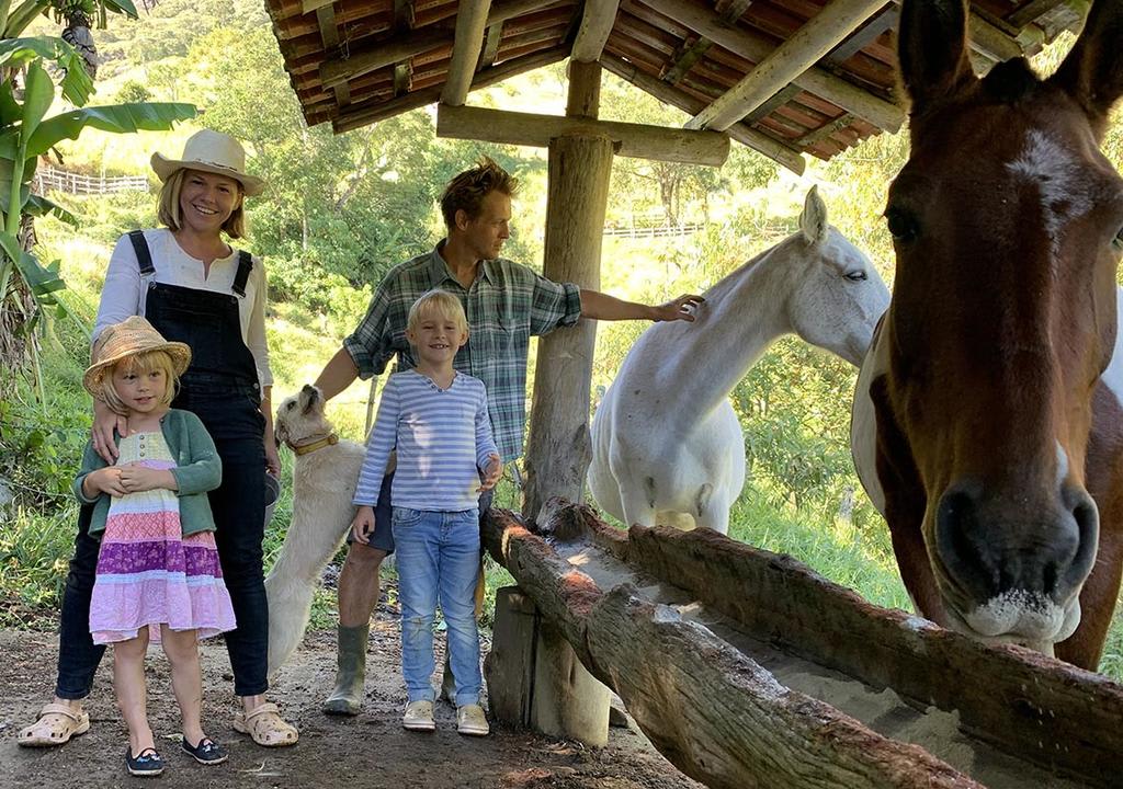 Host family of two adults two kids and a dog in their stable with horses