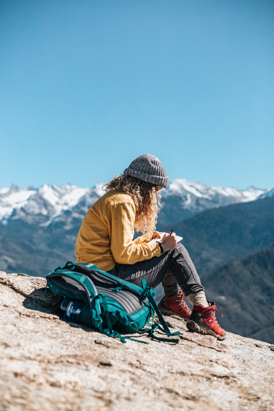 Female adventurer journaling against a mountain backdrop