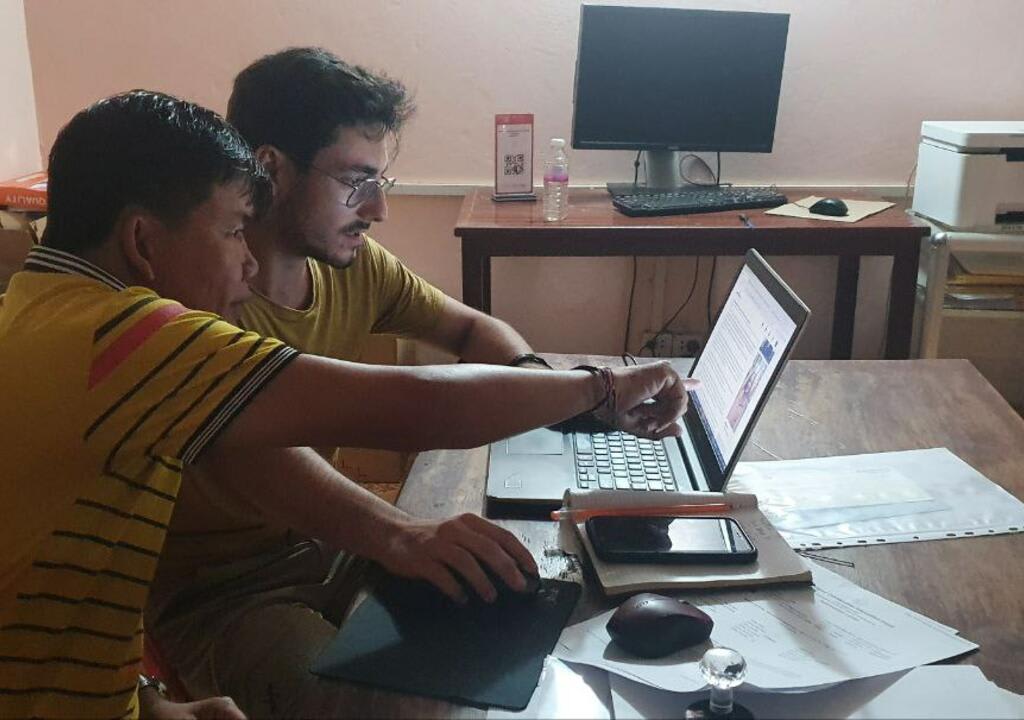 a volunteer and a local using the laptop