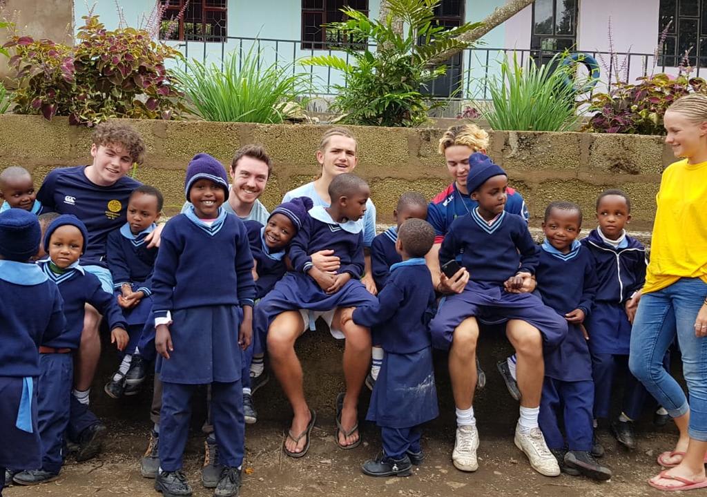 Cinco jóvenes voluntarios en una escuela con niños africanos