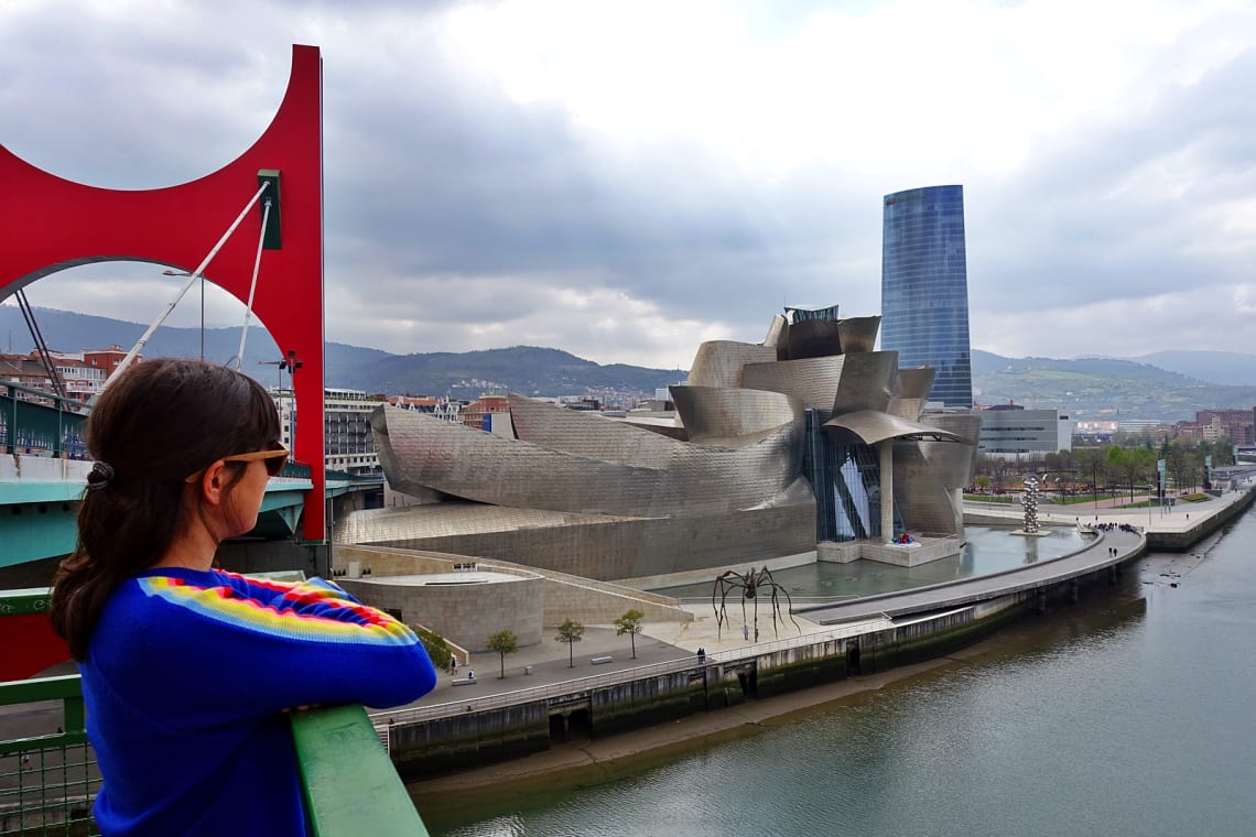 Chica mirando hacia el Museo Guggenheim desde un puente en Bilbao, País Vasco