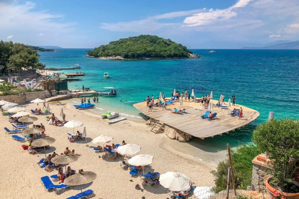 Turistas en una plataforma de madera instalada sobre la orilla de una popular playa de Albania