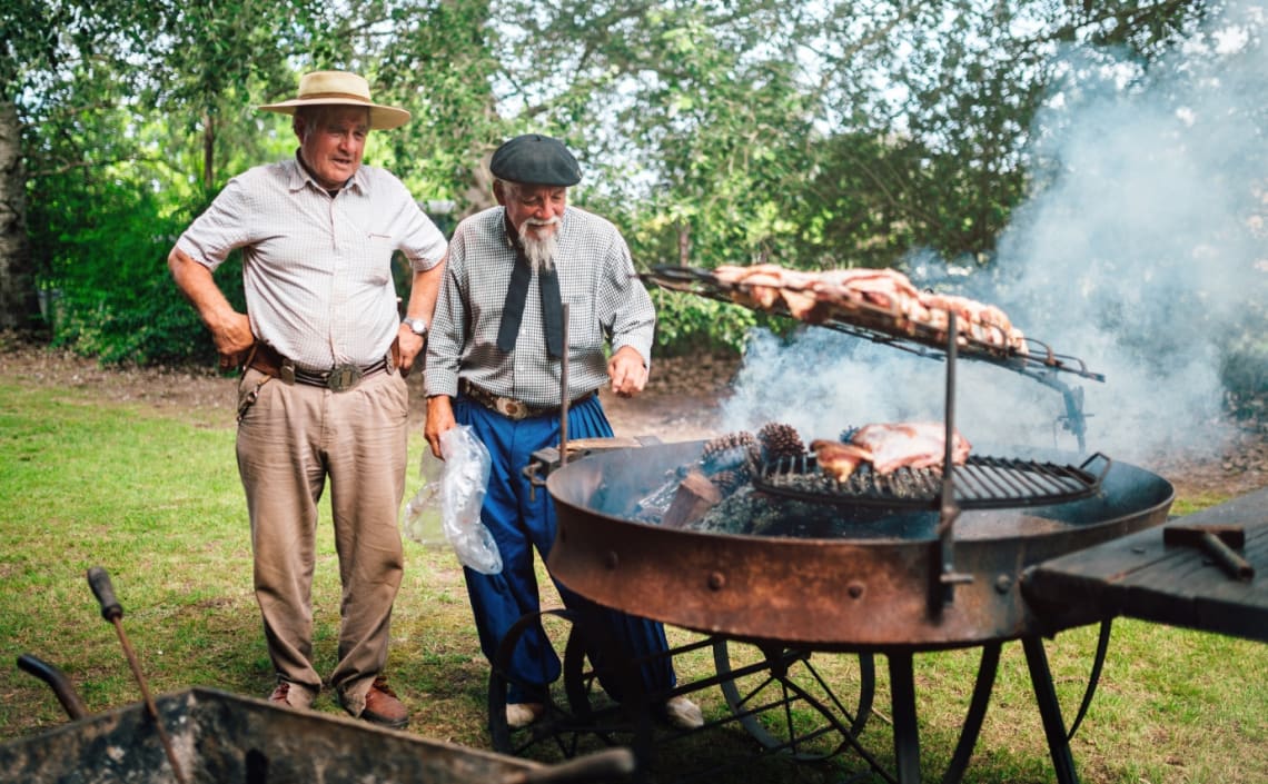 Dos gauchos mayores preparando un asado en un pueblo de Buenos Aires