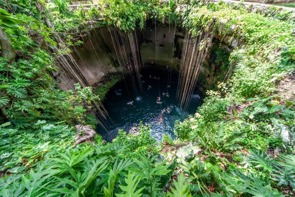 Cenote visto desde lo alto con gente nadando dentro
